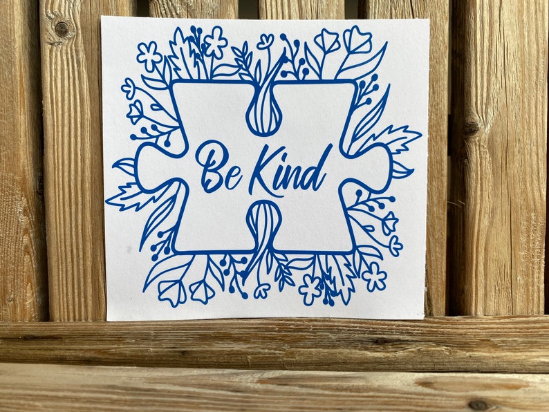 May include: Blue puzzle piece with the words "Be Kind" inside, surrounded by a floral design.