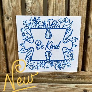 May include: Blue puzzle piece with the words "Be Kind" surrounded by a border of blue flowers and leaves on a white background.