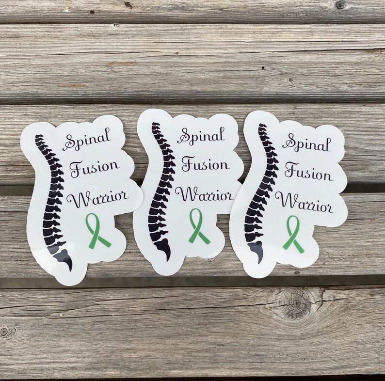 May include: Three white stickers with a black spine illustration and green ribbon. The stickers say "Spinal Fusion Warrior".