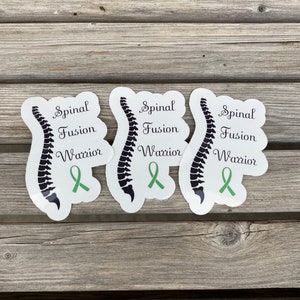 May include: Three white stickers with a black spinal column illustration and green ribbon. The text on the stickers reads "Spinal Fusion Warrior".