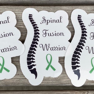 May include: Three white stickers with a black outline of a spine, the words "Spinal Fusion Warrior" and a green ribbon.