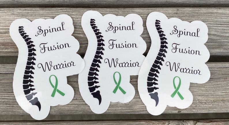 May include: Three white stickers with a black outline of a spine, the words "Spinal Fusion Warrior" and a green ribbon.