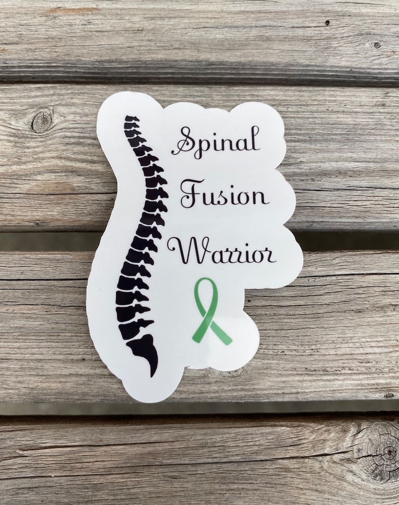 May include: White sticker with a black silhouette of a spine, a green ribbon, and the text "Spinal Fusion Warrior".