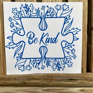 May include: Blue puzzle piece with the words "Be Kind" surrounded by a floral design.