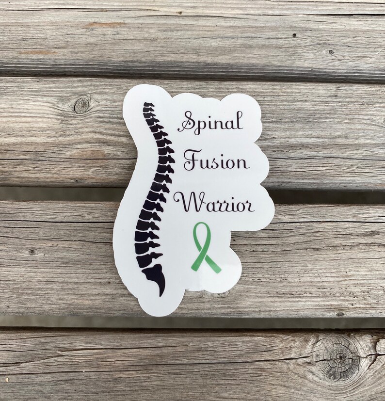 May include: White sticker with a black silhouette of a spine and the text "Spinal Fusion Warrior". A green ribbon is below the text.