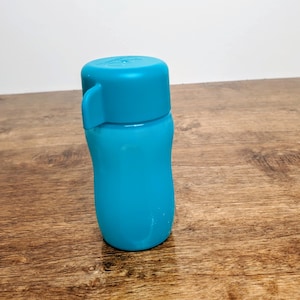 May include: A blue plastic water bottle with a flip top lid. The bottle is on a wooden surface.