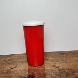 May include: A red plastic container with a white lid. The container has a ribbed texture.