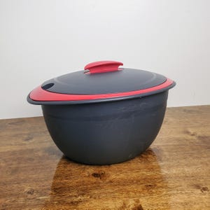 May include: A gray plastic rice cooker with a red lid and a handle. The lid has a small spout for steam to escape.