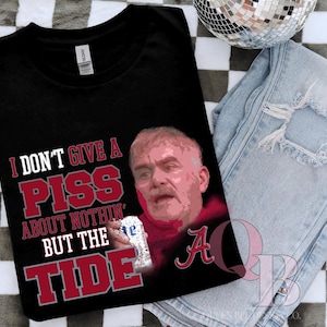 May include: Black t-shirt with the text "I DON'T GIVE A PISS ABOUT NOTHIN' BUT THE TIDE" in red and white. The shirt features a graphic of a man holding a can of beer and the letter "A".