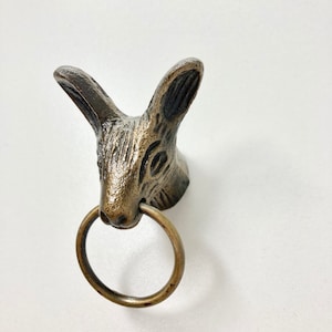 May include: A bronze rabbit head door knocker with a ring pull. The rabbit has a detailed face and ears.