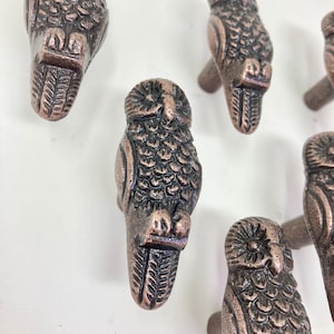 Puede incluir: Conjunto de seis tiradores de cajón de hierro fundido en forma de búho, acabado en cobre. Cada tirador presenta un diseño de búho detallado con alas levantadas y un cuerpo texturizado.