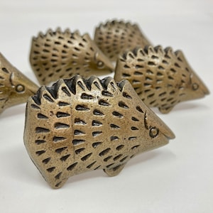 May include: Set of four gold-toned metal hedgehog drawer pulls. Each pull features a detailed hedgehog design with a textured surface.