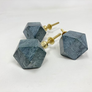 Może przedstawiać: Trzy ciemnozielone marmurowe gałki do szafek z okuciami ze złotego metalu. Każda gałka ma kształt geometrycznego diamentu.