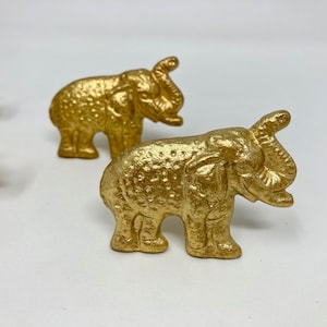 Op de afbeelding: Twee gouden metalen olifantenbeeldjes. De olifanten zijn gedetailleerd met textuur en hebben een licht verweerde afwerking.