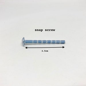 May include: A snap screw, 4.5 cm long, with a round head and threaded shaft. The text "snap screw" is above the screw. The screw is approximately 1.77 inches long.