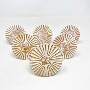 Peut inclure: Six boutons de porte ronds blancs avec un motif soleil doré.