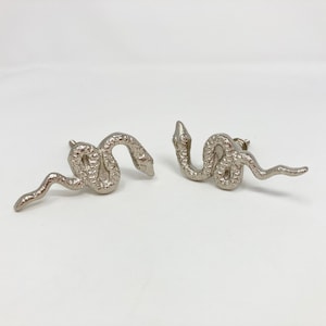 May include: Two silver snake-shaped cabinet knobs with a textured finish.