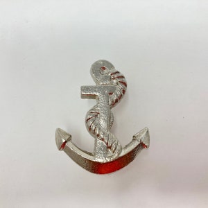 Op de afbeelding: Een zilveren anker met een touwontwerp. Het anker is een decoratief stuk met een nautisch thema.