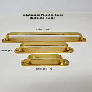 Op de afbeelding: Drie ongelakte gepolijste messing backplate-grepen in verschillende maten: 265 mm, 165 mm en 120 mm.