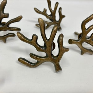 Puede incluir: Cuatro pomos de armario de metal de color dorado con forma de ramas de coral.
