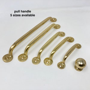 以下が含まれることがあります： 金色調のプルハンドルが5サイズあり、小さいものから大きいものまで揃っています。ハンドルはすべて金属製で、丸みを帯びた形をしています。ハンドルは、小さいものから大きいものまで、一列に並んでいます。ハンドルはすべてピントが合っています。  "pull handle 5 sizes available"