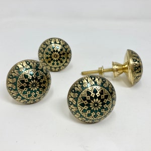 May include: Three gold-toned cabinet knobs with a green and gold mandala design. The knobs are round and have a raised edge.