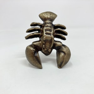 May include: A cast iron lobster figurine with a gold finish. The lobster is standing on its tail with its claws raised.