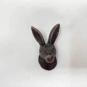 May include: A bronze-coloured rabbit head door knob with a detailed design.