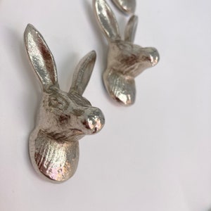 May include: Three silver rabbit head wall hooks. The hooks are made of metal and have a realistic design.
