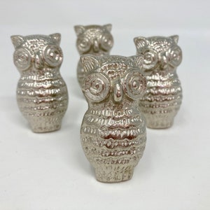 May include: Four silver owl-shaped drawer pulls. The owls have textured feathers and large, round eyes.