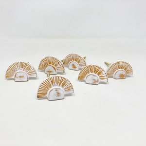 以下が含まれることがあります： 金色の日差し模様の白いセラミック製のキャビネットノブ6個セット。各ノブには、取り付け用の小さなネジ穴が背面にあります。