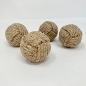 Könnte beinhalten: Vier braune, geknüpfte Seilkugeln. Die Kugeln sind aus natürlicher Jutekordel gefertigt und haben einen Durchmesser von etwa 5 cm.