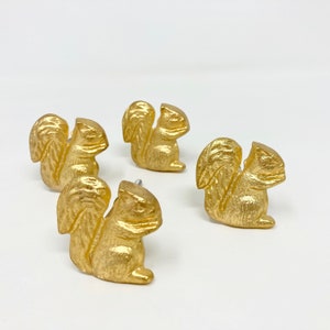 May include: Four gold-painted squirrel drawer pulls. Each pull features a detailed squirrel design with a raised tail and a curled-up body.