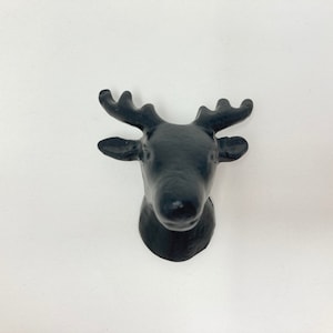 Könnte beinhalten: Schwarzer Wandhaken aus Gusseisen in Form eines Rentierkopfes. Der Haken ist in Form eines Rentierkopfes mit Geweih gestaltet.