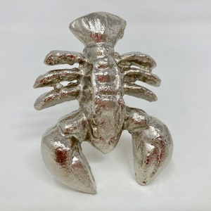 May include: A silver lobster figurine with detailed claws and a textured surface.