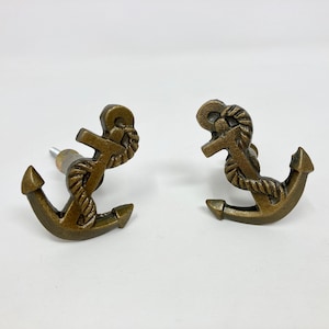 Pode incluir: Dois puxadores de gaveta em forma de âncora de metal dourado com detalhe de corda.