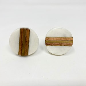 Puede incluir: Dos pomos redondos de mármol blanco con una incrustación horizontal de madera y latón.