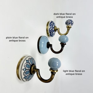 May include: Three ceramic hooks with antique brass bases and blue floral designs. The hooks are in different shades of blue, including plain blue, light blue, and dark blue.