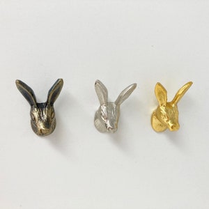 May include: Three rabbit head shaped metal hooks in black, silver, and gold.