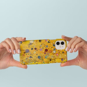 May include: A yellow phone case with a colourful abstract design. The case has a white camera lens cutout.