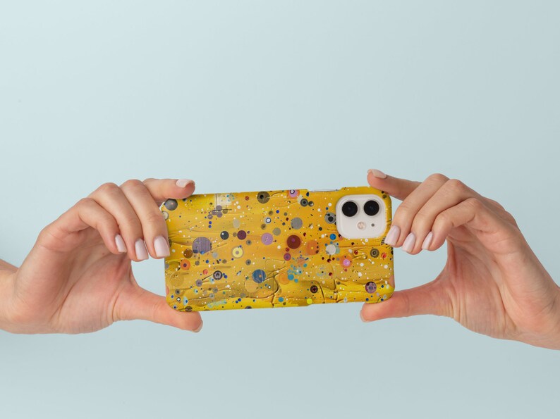 May include: A yellow phone case with a colourful abstract design. The case has a white camera lens cutout.