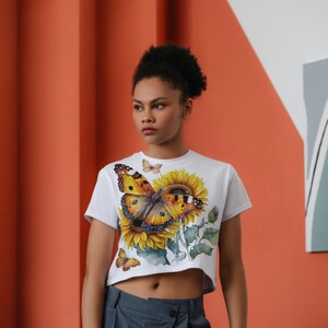 May include: White cropped t-shirt featuring a colourful butterfly and sunflower print.