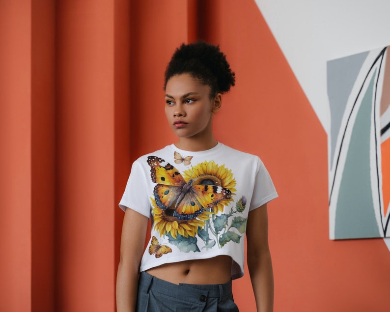 May include: White cropped t-shirt featuring a colourful butterfly and sunflower print.