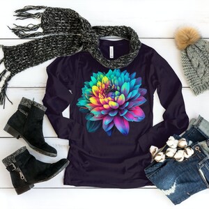 May include: A long-sleeved shirt with a colorful flower graphic on a dark purple background. The shirt is shown with a scarf, a beanie, and jeans.