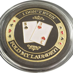 May include: A gold-colored poker chip with a black background and the text "I don't even fold my laundry!"  The chip features two playing cards, an eight of spades and a three of hearts.