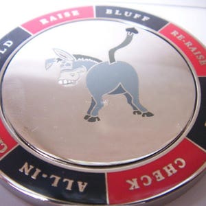 May include: A silver poker chip with a donkey design and the words "Raise", "Bluff", "Re-Raise", "Call", "Check", "Check-Raise", "Fold", and "All-In" around the edge.