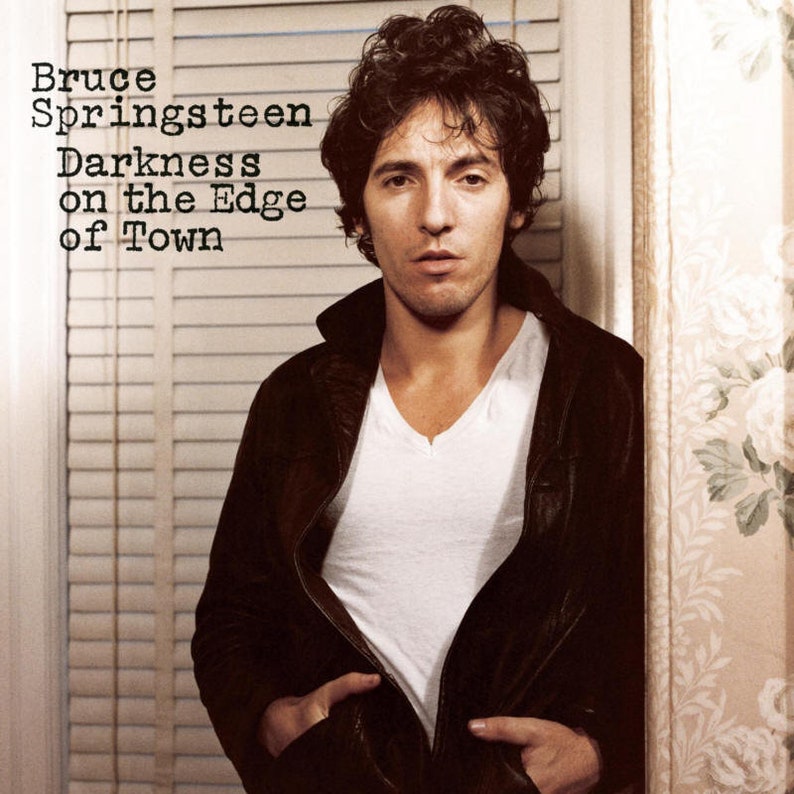 May include: A black and white album cover featuring Bruce Springsteen. The album title is "Darkness on the Edge of Town".