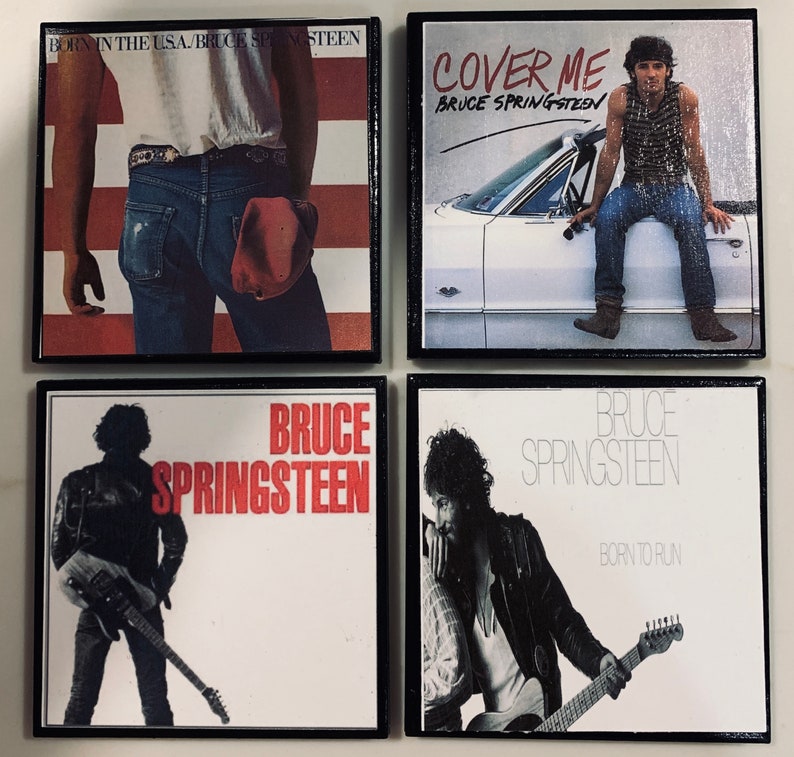 May include: Four black framed album covers with white backgrounds. The covers feature Bruce Springsteen and the album titles "Born in the USA", "Cover Me", "Bruce Springsteen", and "Born to Run".