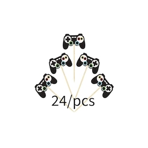 Puede incluir: Un conjunto de 24 toppers de cupcake de mando de videojuego en blanco y negro con botones de colores. Los toppers están en palos de madera.