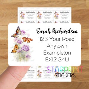 May include: A white rectangular sticker with a floral design featuring butterflies and purple flowers. The sticker includes the text "Sarah Richardson", "123 Your Road", "Anytown", "Exampleton", and "EX12 34U". The sticker also includes the text "STARPRINT STICKERS".